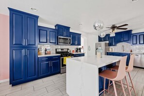 Eine moderne Küche mit blauen Schränken, einer weißen Kochinsel und einem Deckenventilator.