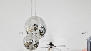 Ein Essbereich mit einem weißen Tisch, Stühlen, einem Deckenventilator und Discokugeln.