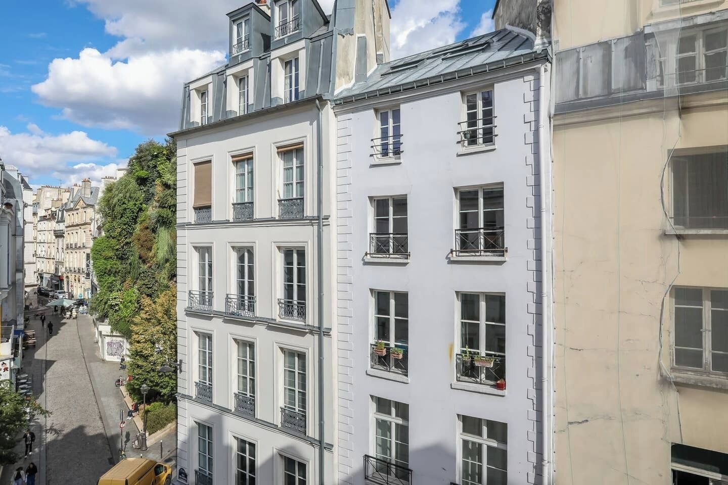 Ein mehrstöckiges Gebäude mit weißer Fassade, zahlreichen Fenstern und Balkonen.