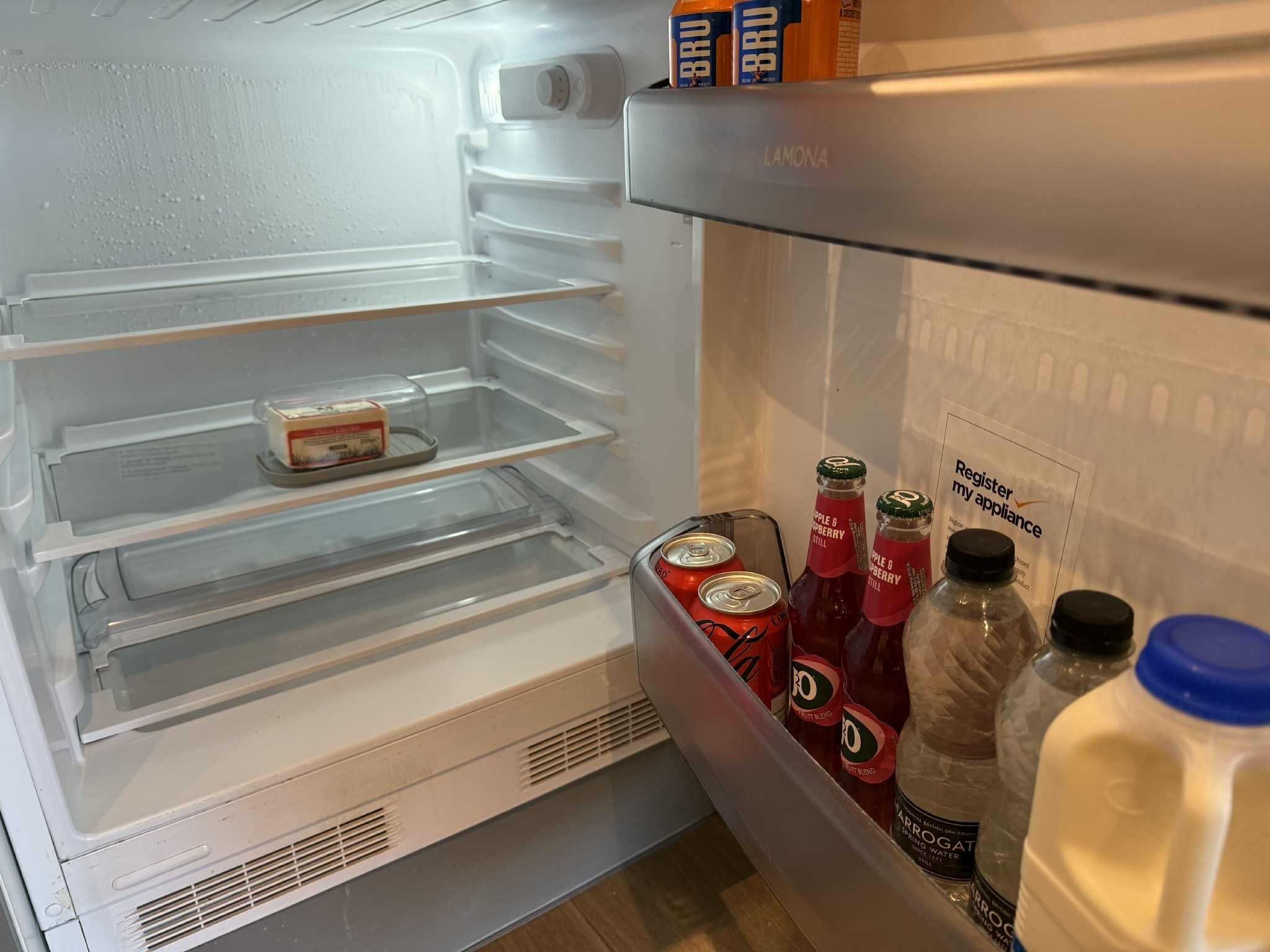 Ein Kühlschrank mit einer Milchpackung, zwei Flaschen Apfel-Erdbeer-Saft und zwei Dosen Diät-Cola.