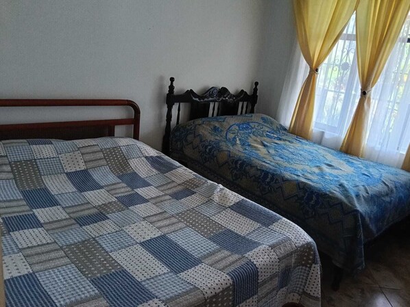 Una habitación con dos camas, una con colcha a cuadros y la otra con cubre cama estampado.