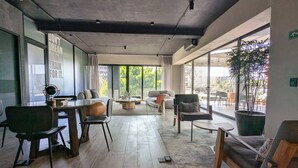 Ein modernes Interieur mit Holzboden, einem runden Couchtisch und einem großen Fenster mit Blick ins Grüne.