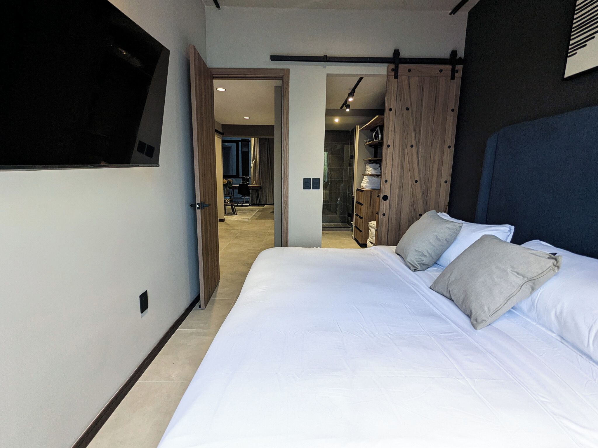 Un dormitorio con una cama grande, un televisor montado en la pared y un armario con puerta corredera.