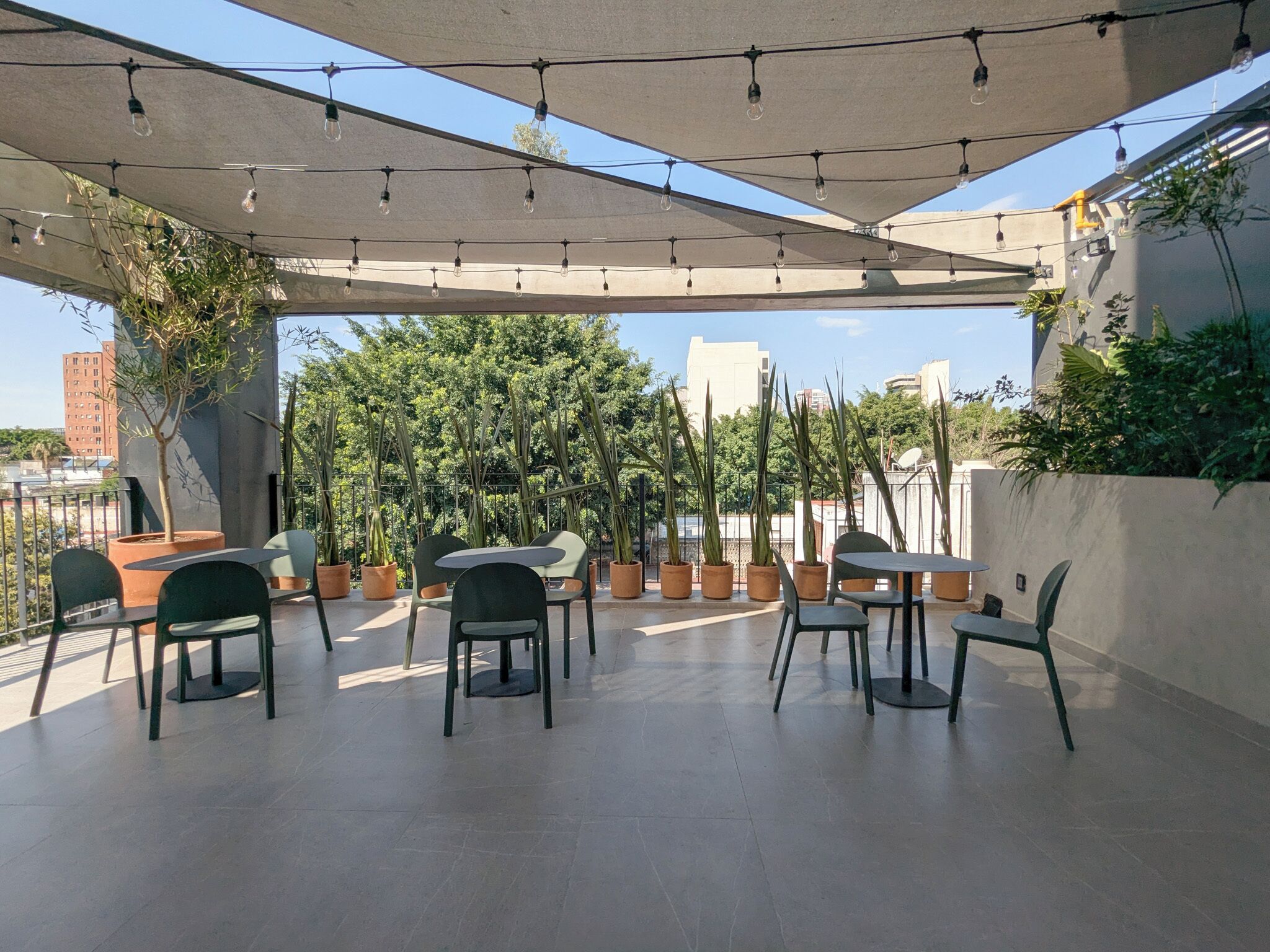 Une terrasse extérieure avec des tables et des chaises, des guirlandes lumineuses et des plantes en pot.