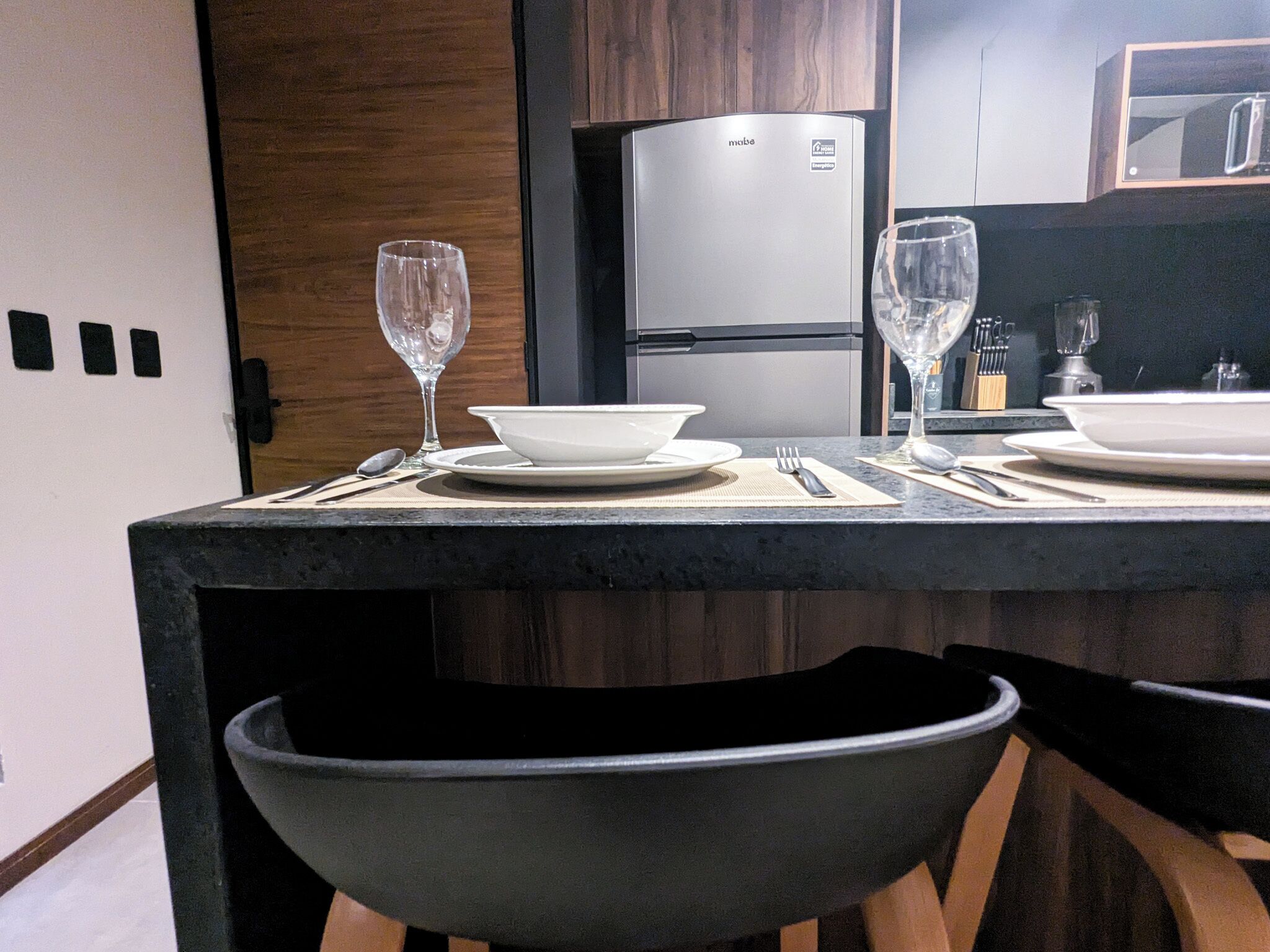 Eine moderne Küche mit Einbaukühlschrank, Esstisch gedeckt mit Tellern, Gläsern und Besteck.