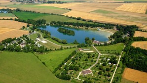 Eine Luftaufnahme einer ländlichen Gegend mit einem See, umliegenden Feldern und verstreuten Gebäuden.