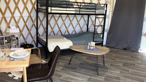 Ein Zimmer mit einem Etagenbett, einem Esstisch mit Stühlen und einem kleinen runden Tisch mit einer Kerze.