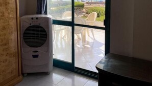 Habitació amb un gran finestral corredís que dona a una zona exterior amb cadires i vista al mar.