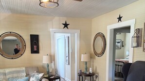 Un salon avec un ventilateur de plafond, une table basse ronde, un fauteuil à rayures et un tapis à motifs.