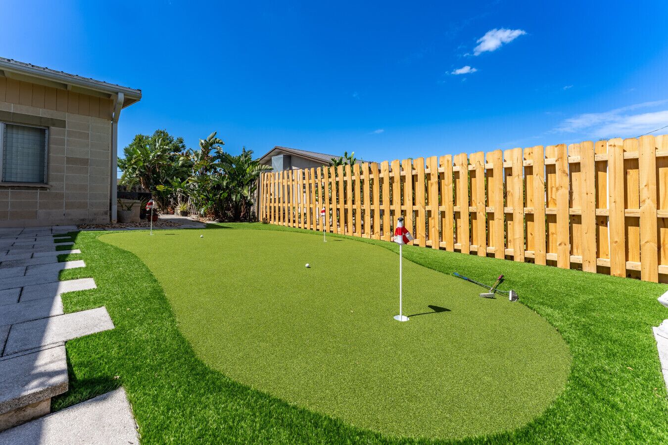Un parcours de golf en gazon synthétique, bien entretenu, agrémenté d’une clôture en bois et d’un mât de drapeau.