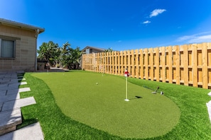 Ein gepflegter Rasenplatz für Golf mit Kunstgrashabitate, einem Holzzaun und einer Fahne.