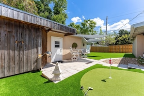 Ein Garten mit Terrasse, Kunstgrasanlage, Grill und Gartenmöbeln.