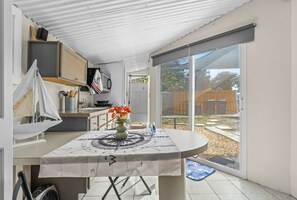 Eine Küche mit Esstisch, einem Modell eines Segelboots und einem Fenster mit Blick auf einen Garten.