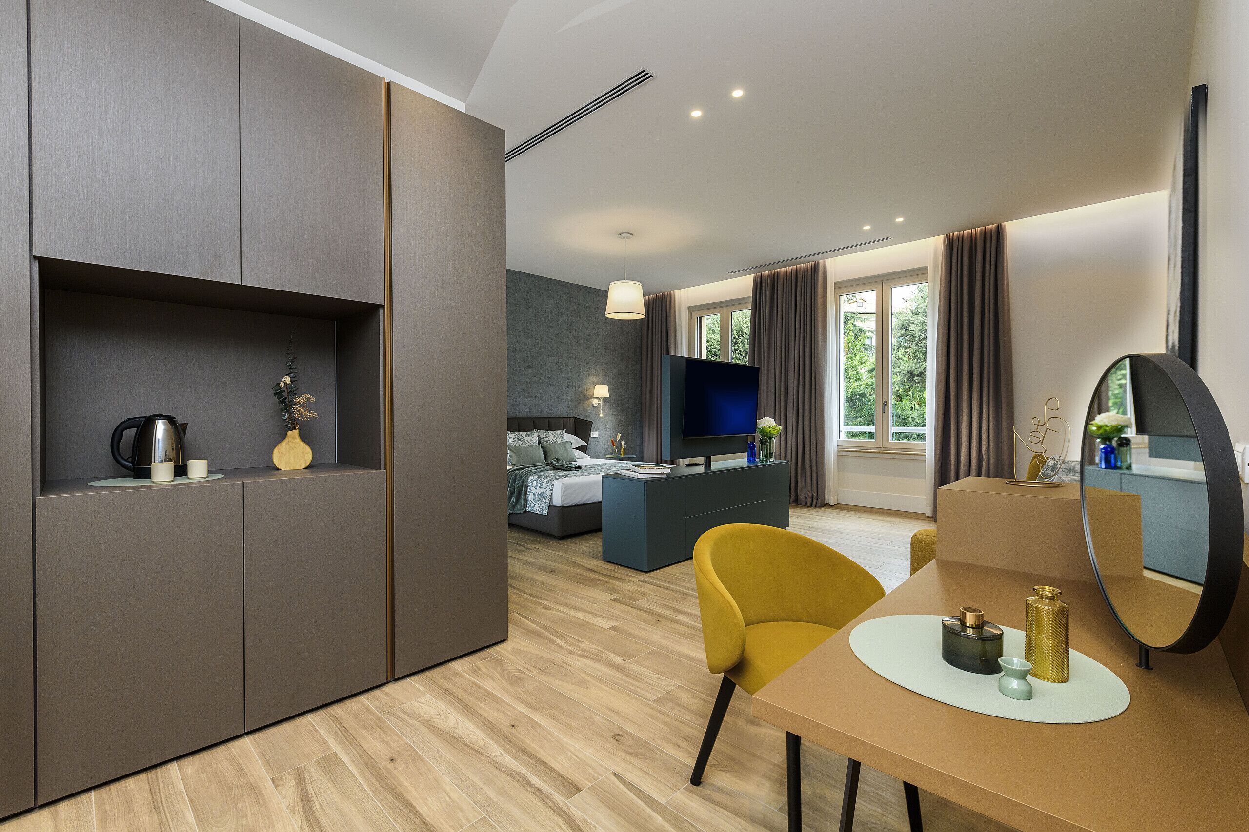 Una habitación de hotel moderna con una cama, un televisor, un escritorio con una silla y un ventanal grande.