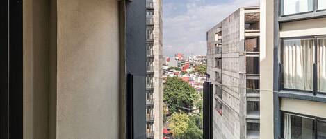Un balcón con vistas a edificios cercanos y un árbol.