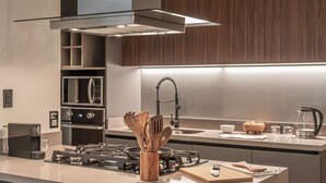 Uma cozinha moderna com fogão a gás, eletrodomésticos em aço inoxidável e armários de madeira.