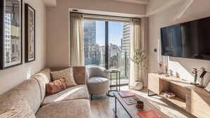 Uma sala de estar moderna com sofá, poltrona, televisão e uma obra de arte na parede.