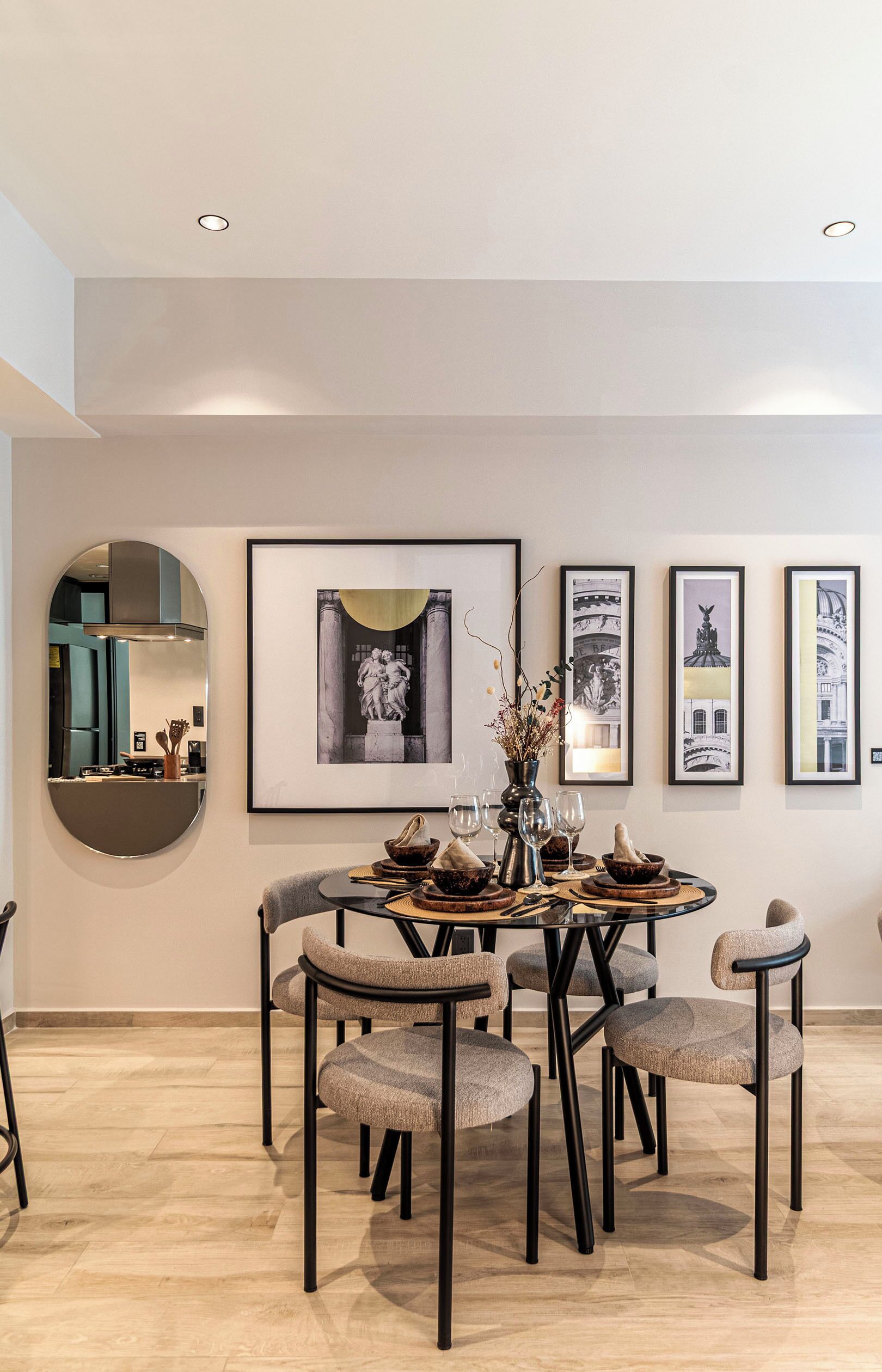 A dining area with a round table, six chairs, and framed artwork on the wall.