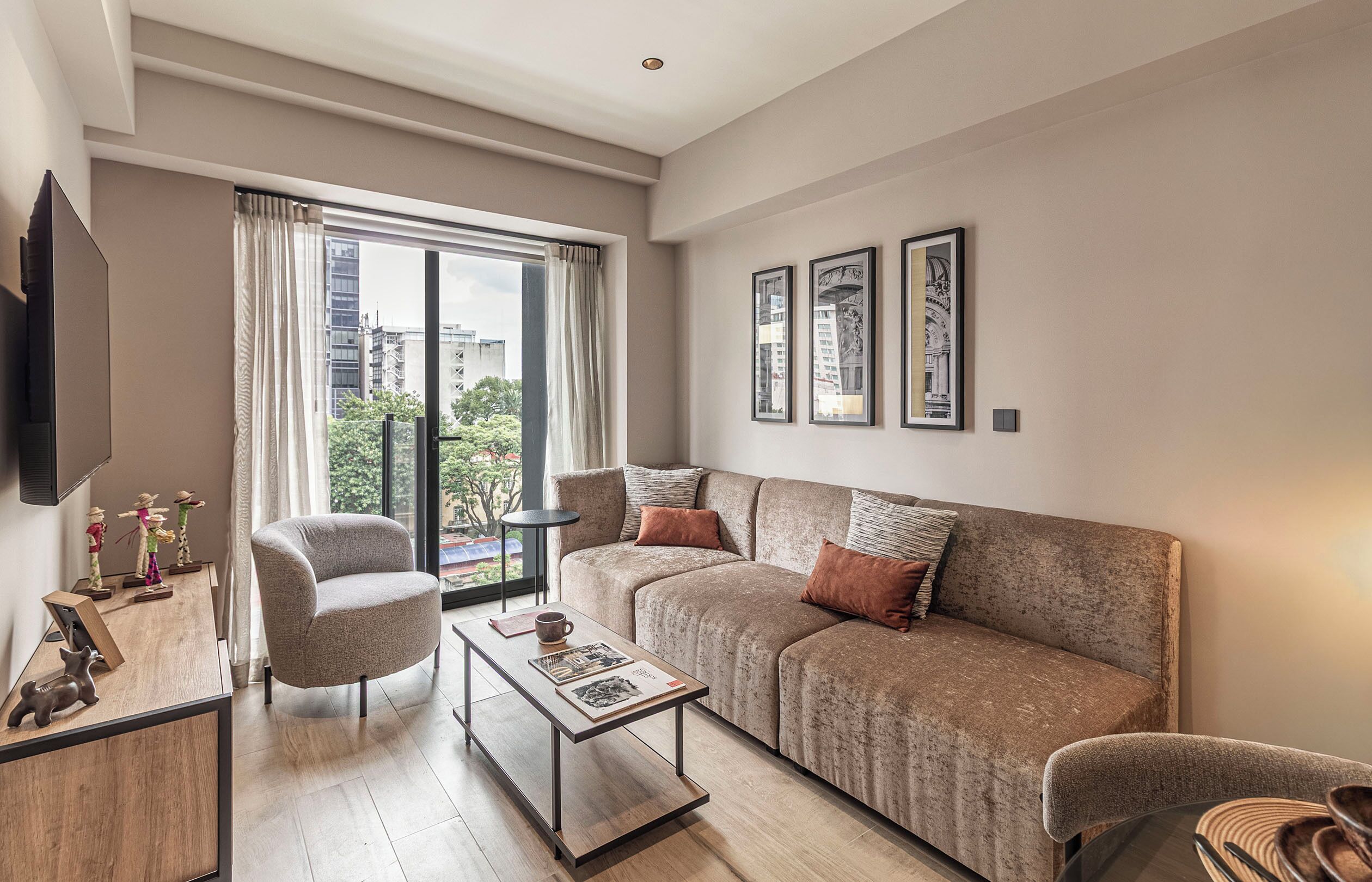 A modern living room with a sofa, armchairs, a coffee table, and a TV mounted on the wall.