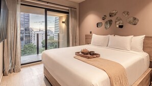 Quarto de hotel com uma cama grande, vista para a paisagem urbana e arte decorativa na parede.