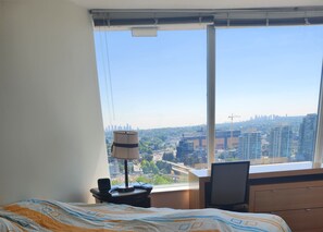 A hotel room with a large window, a bed, a desk, and a lamp. - Pets ok View Suite 3 bed (2 bed + den) 2 bath, 1201 Sqft. Rogers Arena Skytrain (Vancouver)