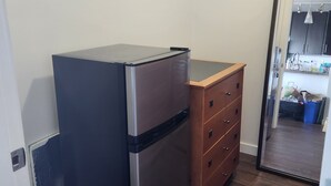 A compact kitchen with a refrigerator, wooden dresser, and a doorway leading to a dining area.