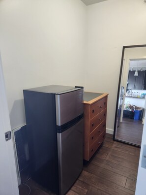 A compact kitchen with a refrigerator, wooden dresser, and a doorway leading to a dining area. - Pets ok View Suite 3 bed (2 bed + den) 2 bath, 1201 Sqft. Rogers Arena Skytrain (Vancouver)