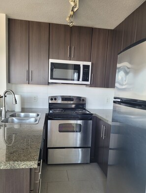 A modern kitchen with stainless steel appliances, a microwave, oven, and refrigerator. - Pets ok View Suite 3 bed (2 bed + den) 2 bath, 1201 Sqft. Rogers Arena Skytrain (Vancouver)