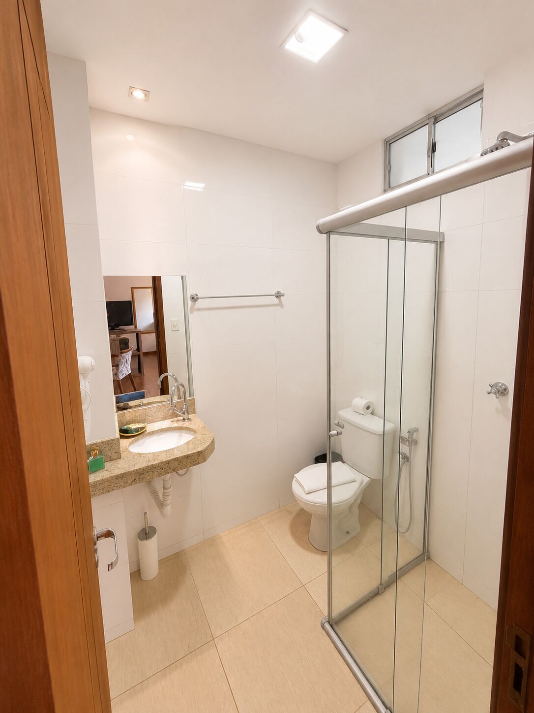 Un baño moderno con cabina de ducha de vidrio, un lavamanos con espejo y un inodoro.