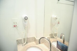 A bathroom with two hair dryers mounted on the wall, a sink with a mirror, and a towel rack above the sink. - Cambraia Hotel Arcos (Arcos)