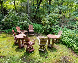 A circular outdoor seating arrangement with wooden chairs and tables, surrounded by lush greenery and trees. - Escape to the Cabin Between the Creeks a 2-bedroom house in Sugar Mountain, NC (Sugar Mountain)