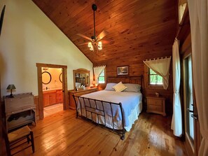 A wooden-paneled bedroom with a bed, bedside tables, a mirror, and a ceiling fan. - Escape to the Cabin Between the Creeks a 2-bedroom house in Sugar Mountain, NC (Sugar Mountain)