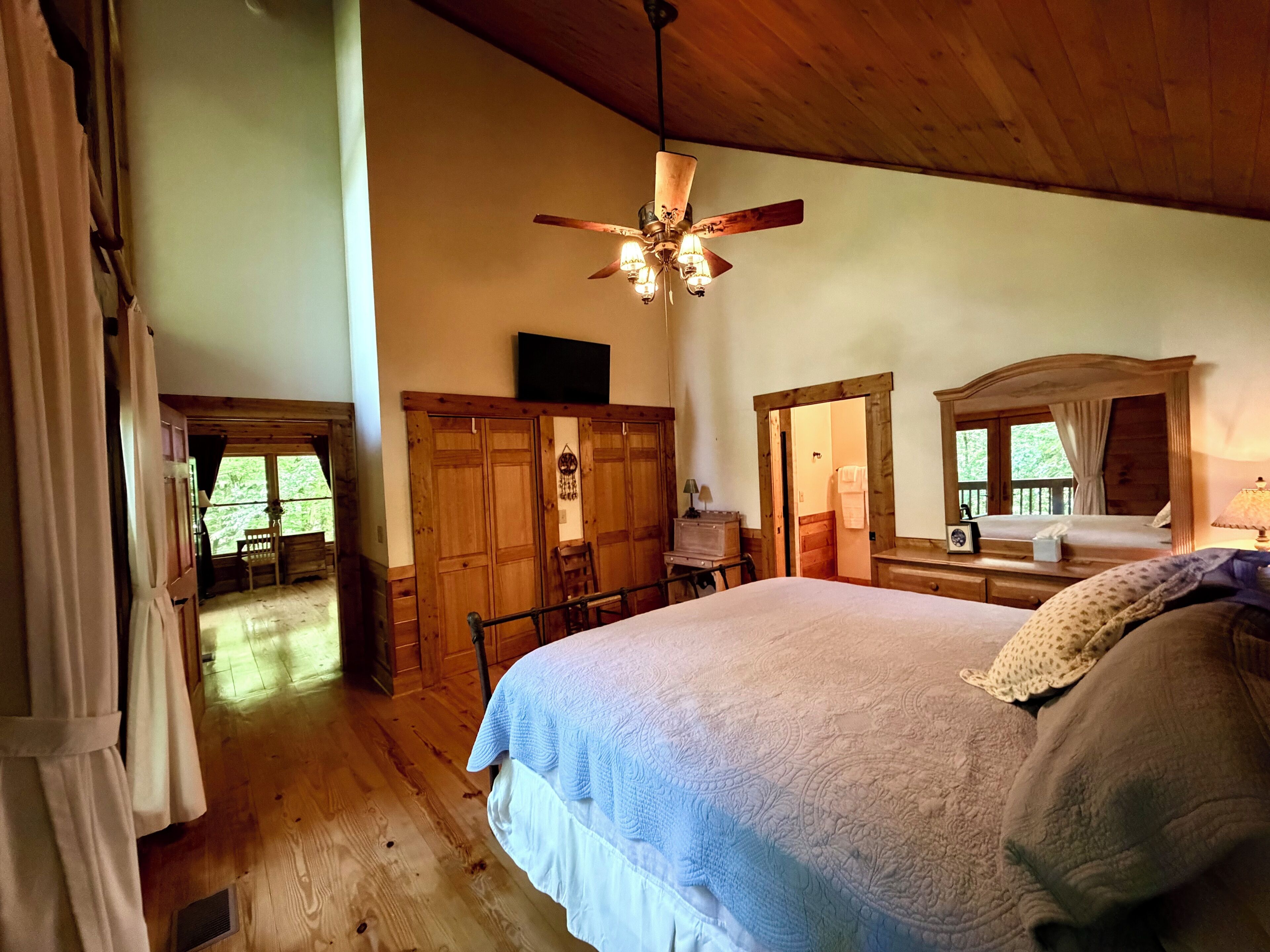 Un dormitorio con cama, techo de madera y ventilador de techo.