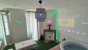 Une chambre avec un lit, une petite table, un écran de projection diffusant une chaîne de télévision et une piscine.