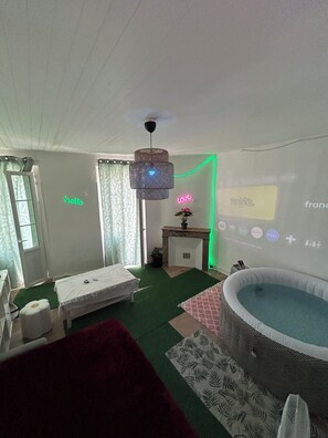 Ein Zimmer mit einem Bett, einem kleinen Tisch, einer Projektionsleinwand, auf der ein Fernsehsender läuft, und einem Pool.