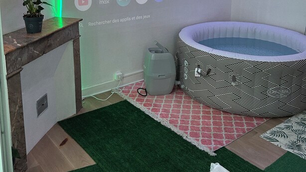 Une pièce avec une piscine, un panneau lumineux au néon et un écran de télévision diffusant un service de streaming.