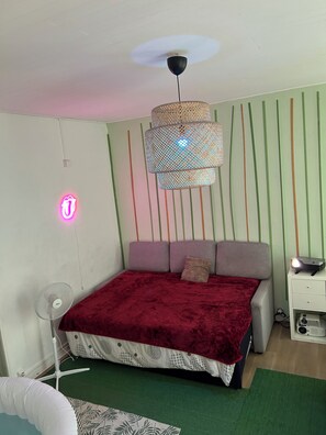 A bedroom with a bed, a standing fan, a projector, and a wall-mounted lamp. - An entire apartment with a jacuzzi in the heart of Bordeaux (Bordeaux)