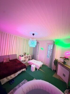 A room with a bed, a desk, a chair, a small table, and a neon sign. - An entire apartment with a jacuzzi in the heart of Bordeaux (Bordeaux)