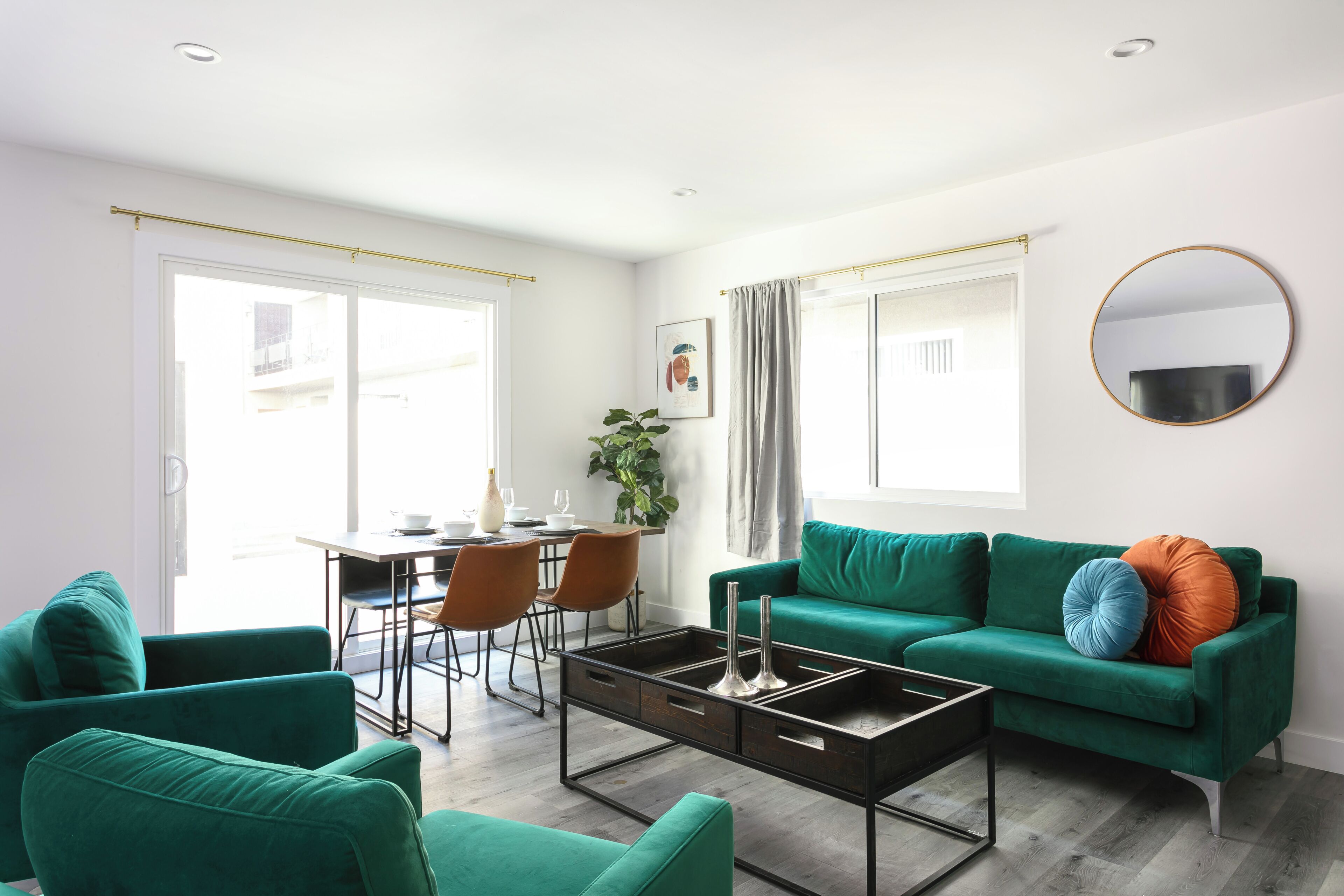 Un salon moderne avec un canapé vert, une table basse et un coin repas comprenant des chaises et une table.