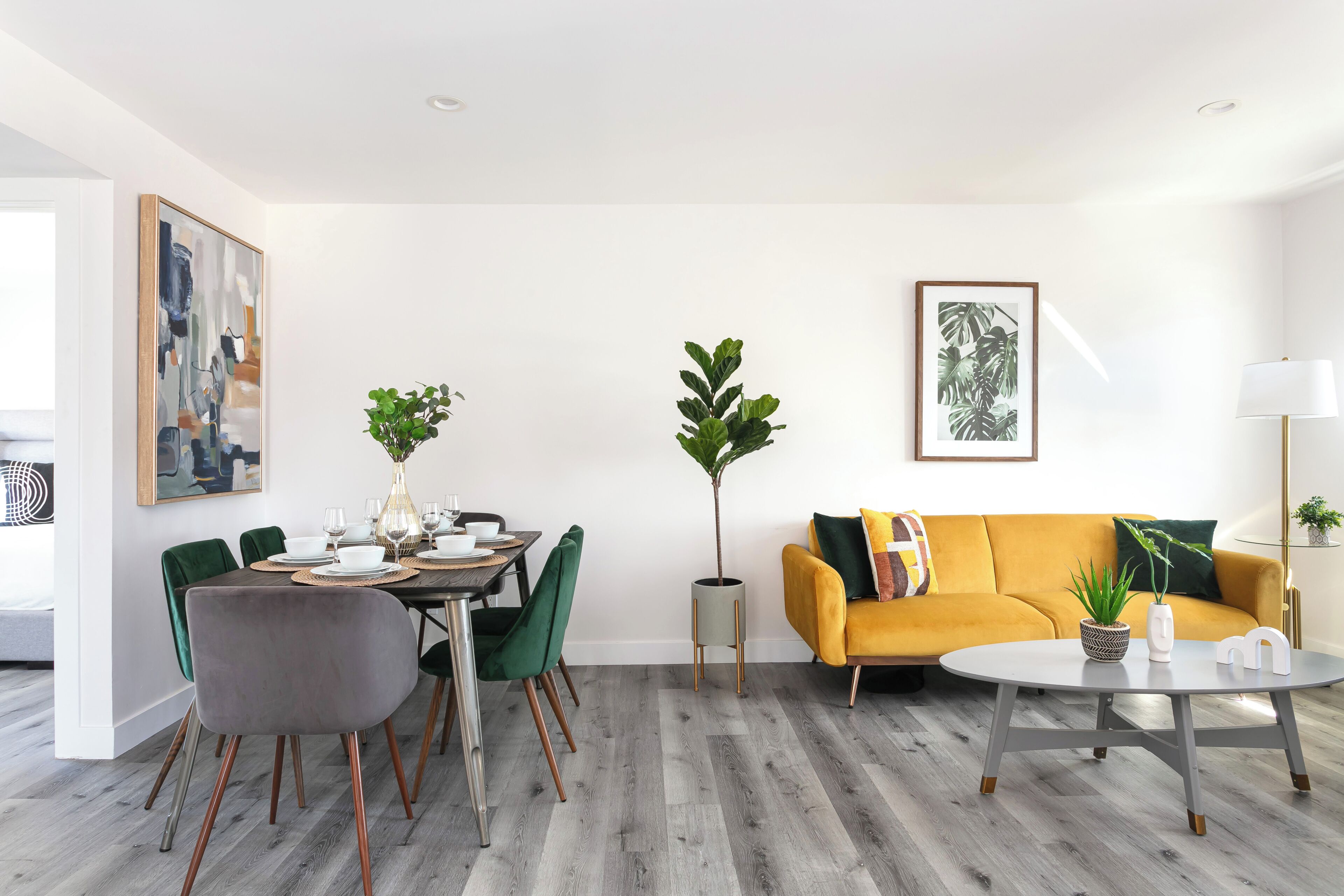 A modern living room with a dining area, featuring a sofa, a coffee table, and a dining table with chairs.