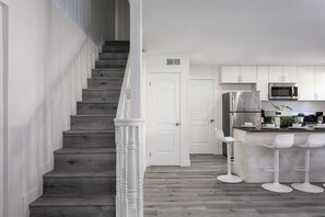 A modern kitchen with a central island, stainless steel appliances, and white cabinetry. - Chic City Apt Near Americana Glendale (Glendale)
