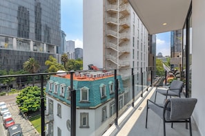A balcony with a view of a cityscape, including modern buildings and a historic building with a green roof.