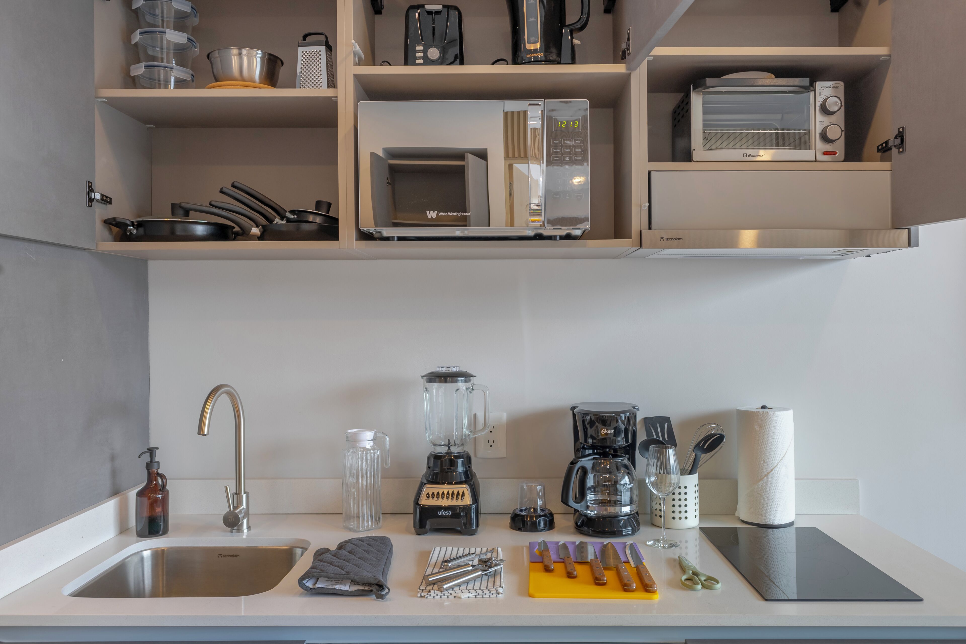 Een keuken met een spoelbak, een magnetron, een koffiezetapparaat en diverse keukengerei.