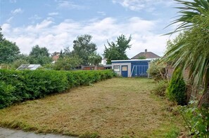 A grassy backyard with a small shed and a house in the background. - super king size bed room with cozy and big bed for 3 in fmaily home (Hornchurch)