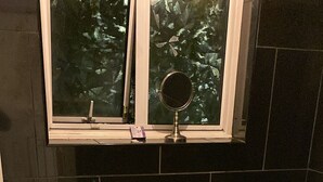 A bathroom with a toilet, sink, and bathtub, a window with a view of trees, and a small trash can. - super king size bed room with cozy and big bed for 3 in fmaily home (Hornchurch)