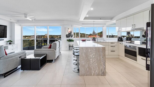 A modern apartment with a living area, kitchen, and large windows offering a city view. - The Surf Breeze Retreat (Coolangatta)