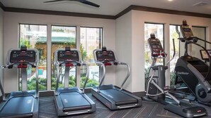 Een sportschool met loopbanden, een stairmaster en een hometrainer.