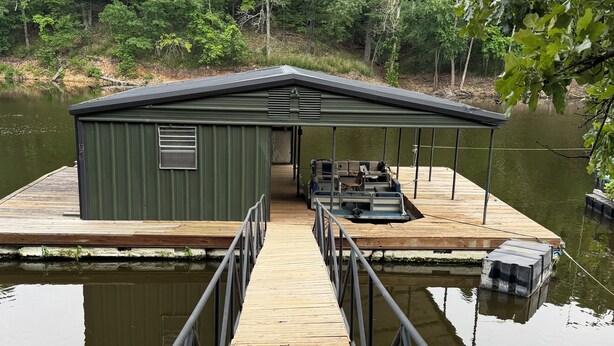 A dock leading to a green building with a covered seating area. - 3+bed 3 bath w/2 slip covered dock,on a cove in Duck Creek parking for trailers (Afton)