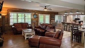 A spacious living room with leather sofas, a dining area with wooden chairs, and a kitchen with modern appliances. - 3+bed 3 bath w/2 slip covered dock,on a cove in Duck Creek parking for trailers (Afton)