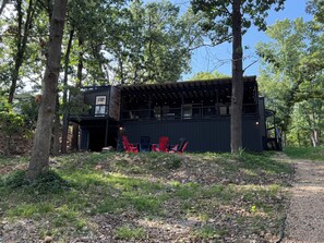 A two-story building with a covered outdoor seating area and red chairs. - 4 bed 3 bath 2 slip covered dock,on a cove in Duck Creek parking for trailers (Afton)